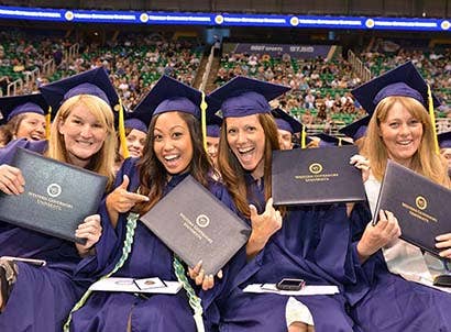 Four WGU graduates holding up their diplomas
