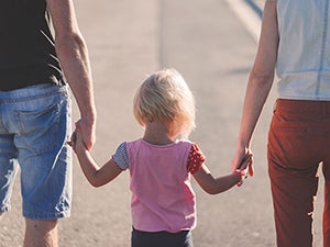 back view of two parents holding child's hands