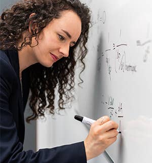 Woman writing math formulas on a whiteboard