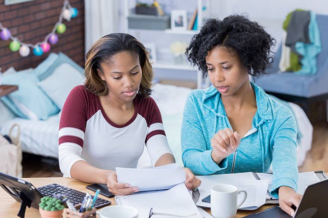 Mother and teenage daughter sitting at desk looking at papers together