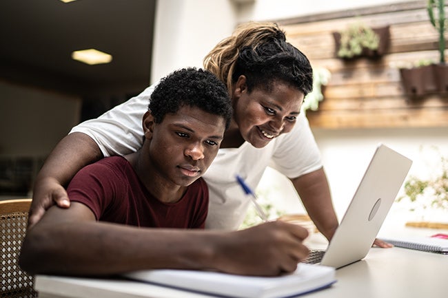 Mother with teenage son looking at laptop together