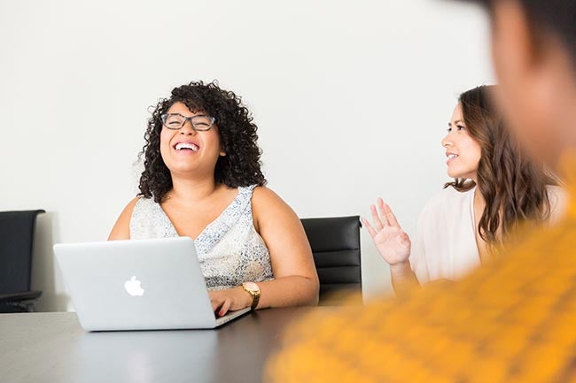 women laughing at her laptop with her co workers