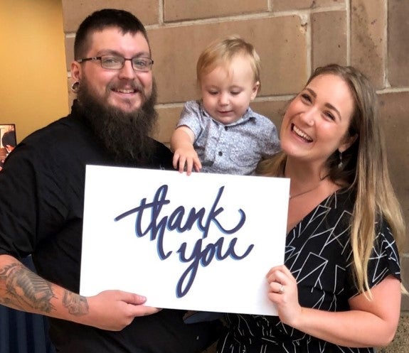 Mom holding her son holding up a thank you sign