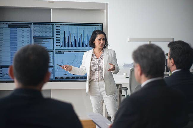 Women presenting in business attire to a group of people 