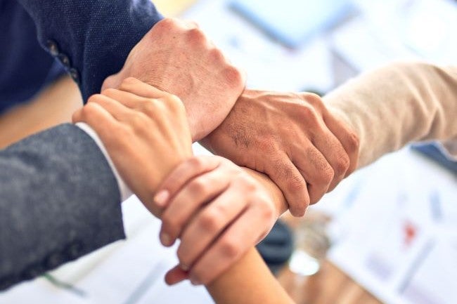 Four people holding wrists in a fireman's hold