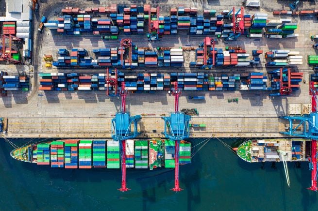 Overhead photo of cargo ship docked at port with colorful cargo boxes on the ship and on shore