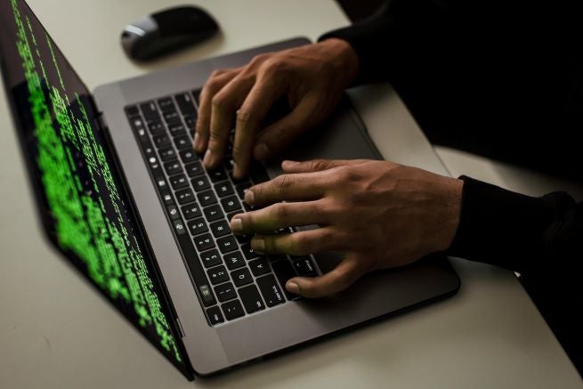 A person's hands on a laptop computer with code on the screen