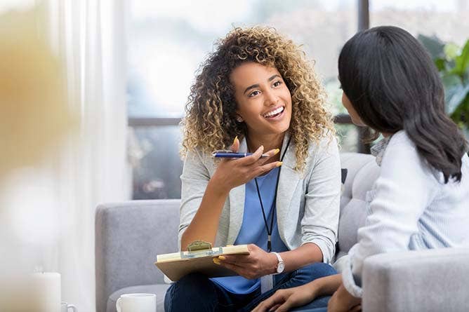 Healthcare professional talking to woman while smiling and writing notes