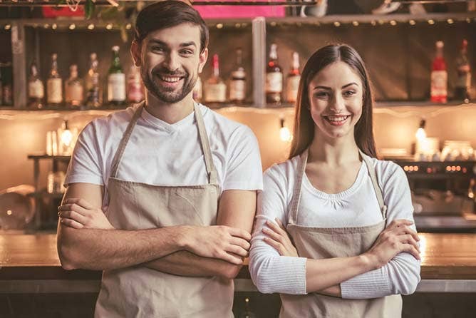 Beautiful young baristas are looking at camera and smiling while standing at the bar counter in cafe; Shutterstock ID 572276110; PO: 123