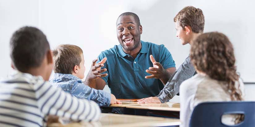 A man enthusiastically teaches students in front of him.