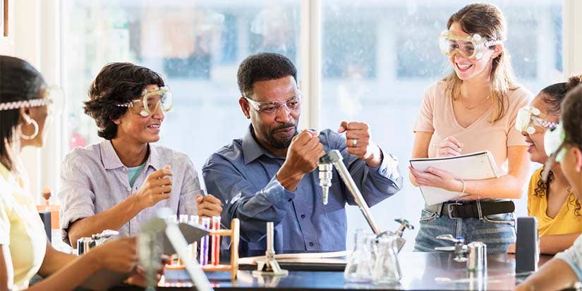 A middle-aged chemistry teachers guides his students through some hands-on experiments.