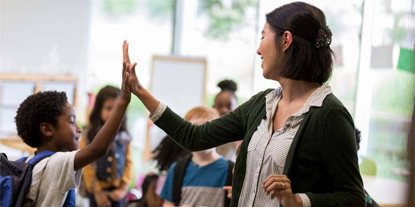 A teacher high-fives one of her students.