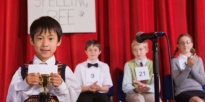 Young Student holds a trophy after winning a spelling bee.