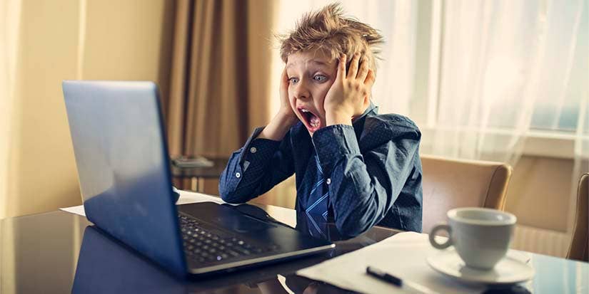 Frustrated child screams at a laptop screen.
