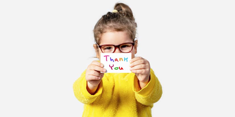 Child in yellow sweater and glasses holds up thank you card. 