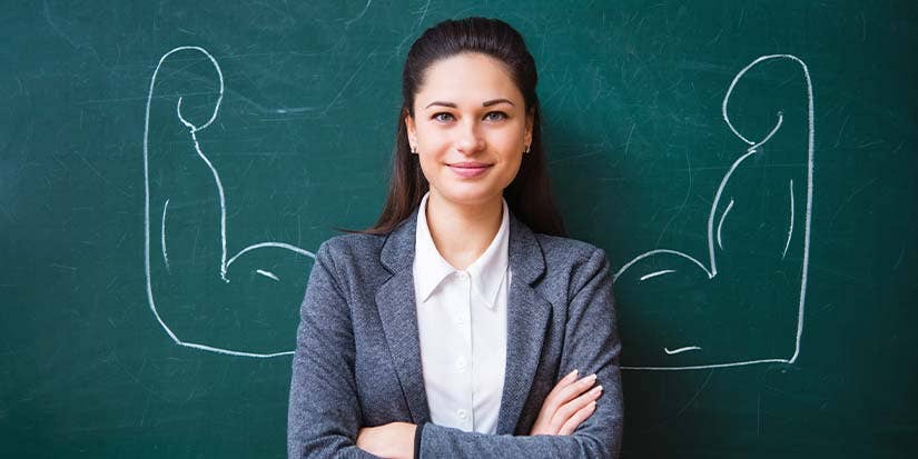 Female teacher stands in front of chalkboard with muscles drawn behind her.  