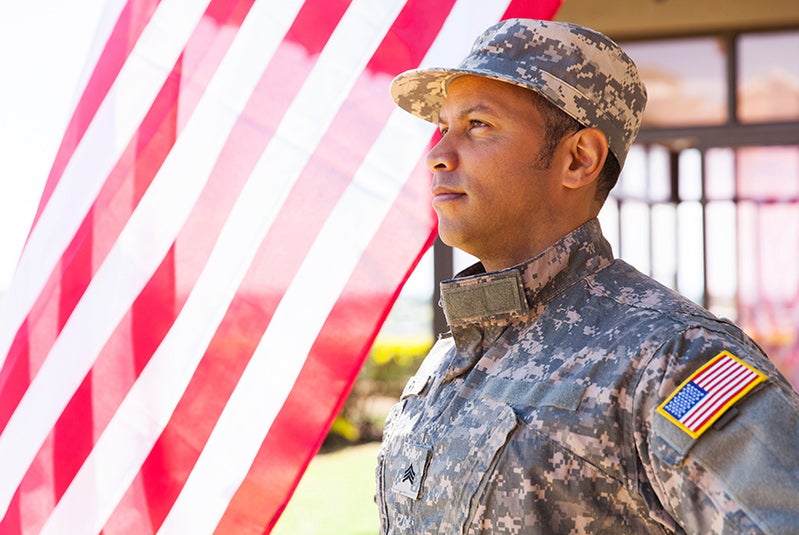 Military person standing next to flag