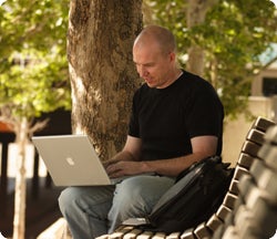 Man on park bench with laptop