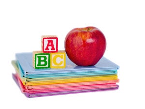 Red apple and blocks sit on stack of books