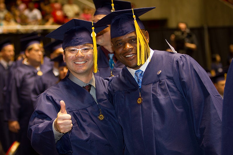 Graduates thumbs up commencement