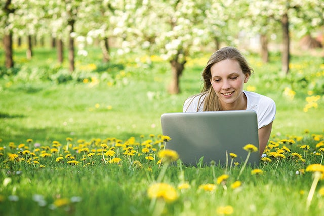 Woman on laptop in meadow