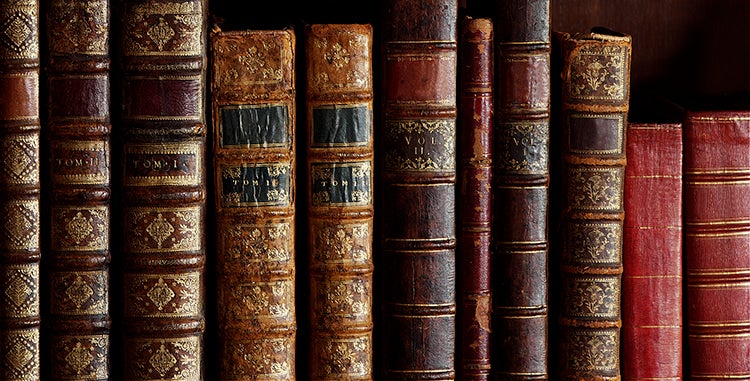 A row of antique books on a shelf.