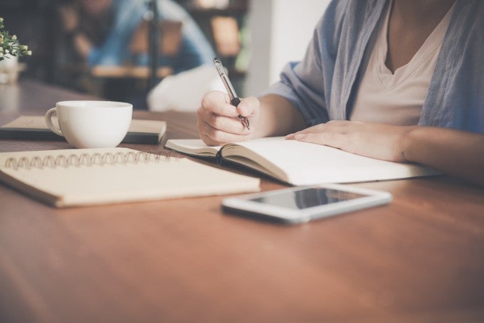 Student taking notes for online degree program