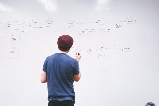 Man in beanie writing on whiteboard | startup