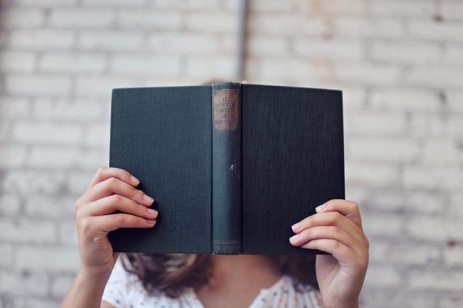 Woman holding book up to face | learning