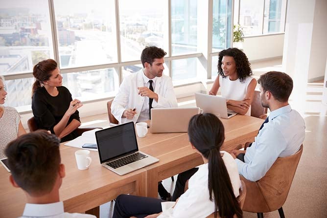 Medical staff sit around a conference table discussing business things.