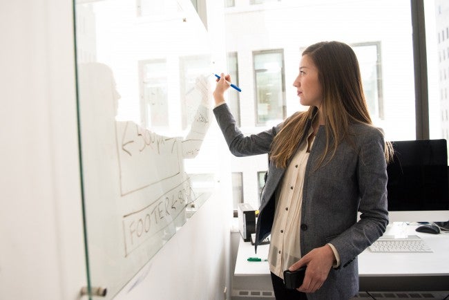 Woman writing on whiteboard | HCM