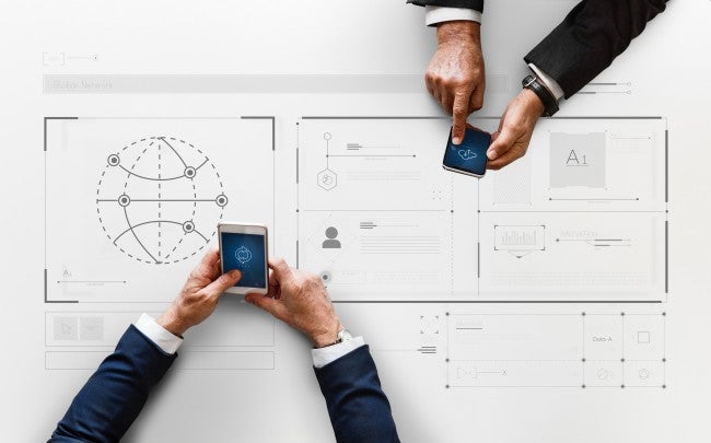 Hands holding phones over spreadsheet of big data