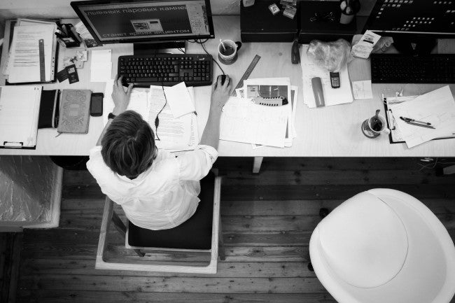 Man sitting with papers at computer | human capital