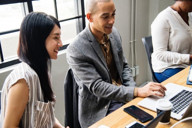 Two people looking at computer, seeming excited