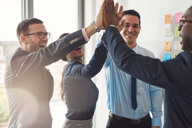 A group of business professionals high-five after a successful meeting.