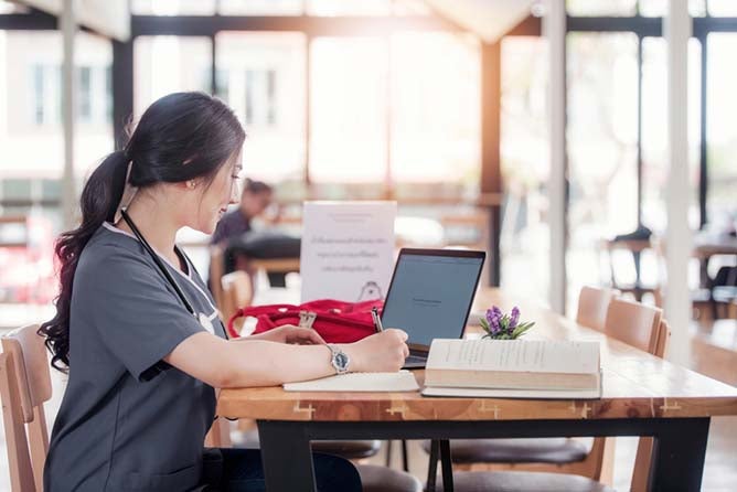 A doctor or nurse works at a laptop as she furthers her education with a bachelor of science in nursing.