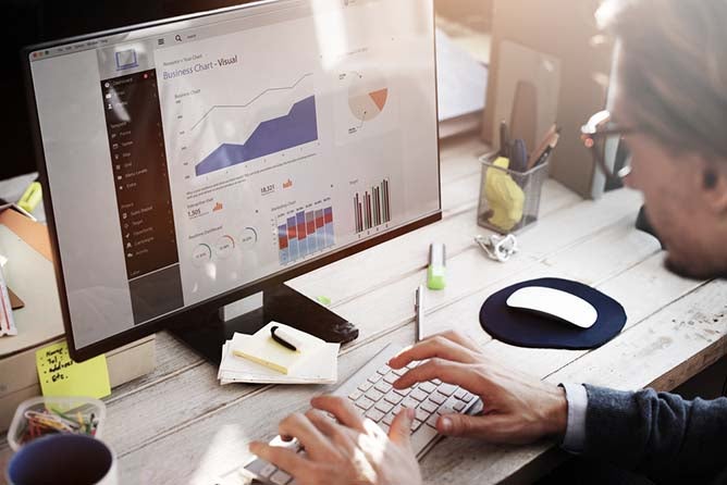 A man looks over different visual data while sitting at a desk.