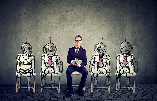 A young businessman sits in the middle of a group of illustrated robots.