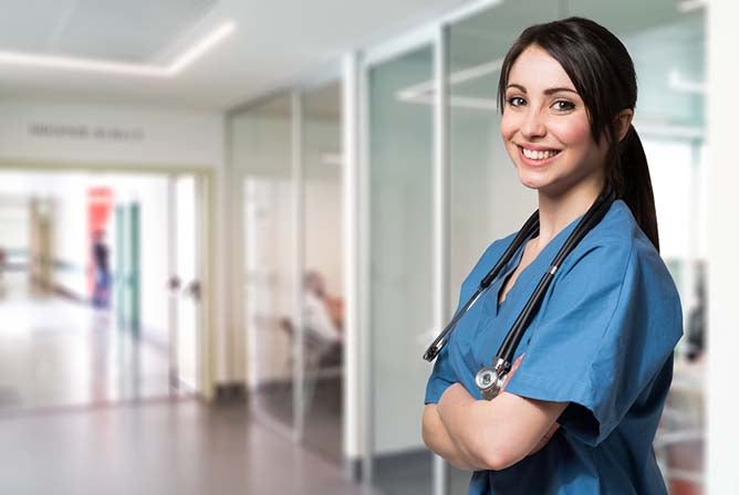 A young nurse poses and smiles in a hallway.