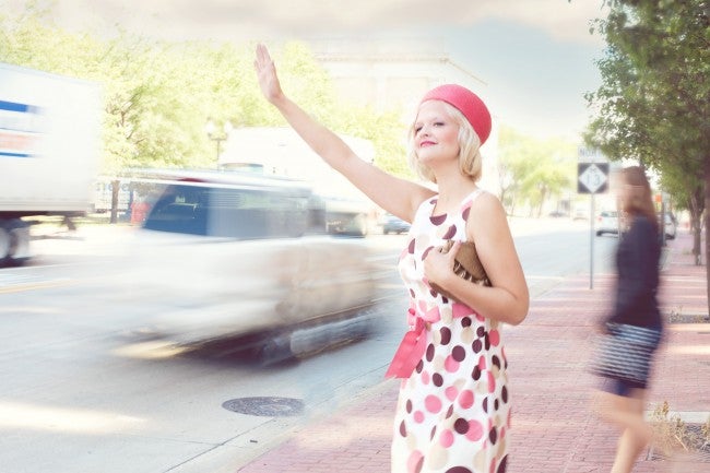 Woman waving down a car on busy road
