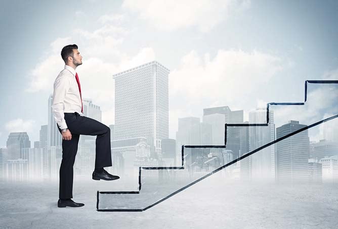 Man in slacks and tie climing an illustrated stairway