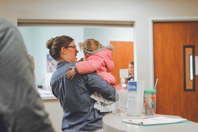 Mom holding daughter at clinic check in