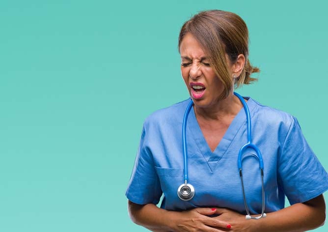 A nurse holds her stomach while making a disgusted look.
