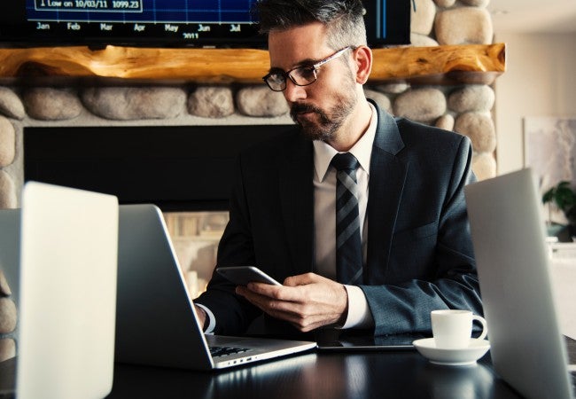 Man on computer holding phone, working on ethics