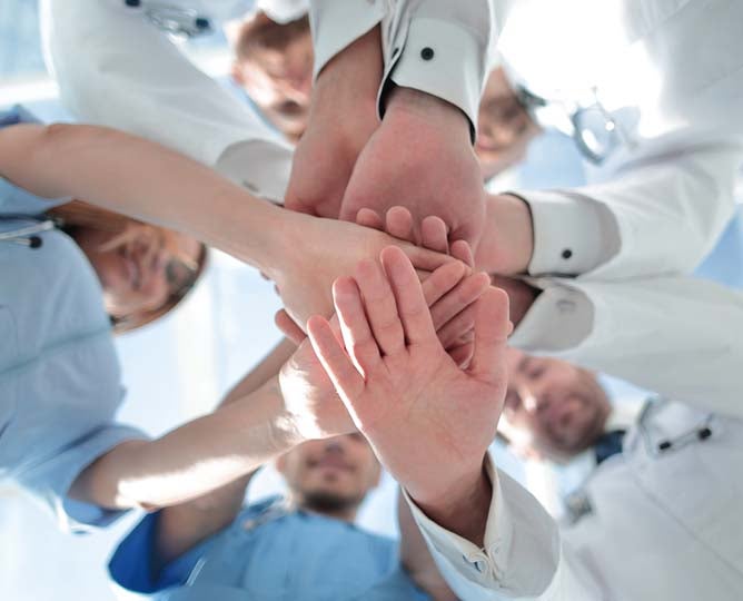 A medical team bring their hands together in the spirit of team unity.