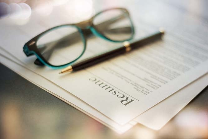 Close-up photo of a resume with a pair of glasses and a pen.