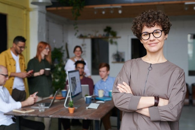 Woman standing in front of group, computer, table