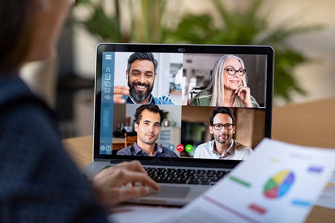A team meets via teleconference on a computer.