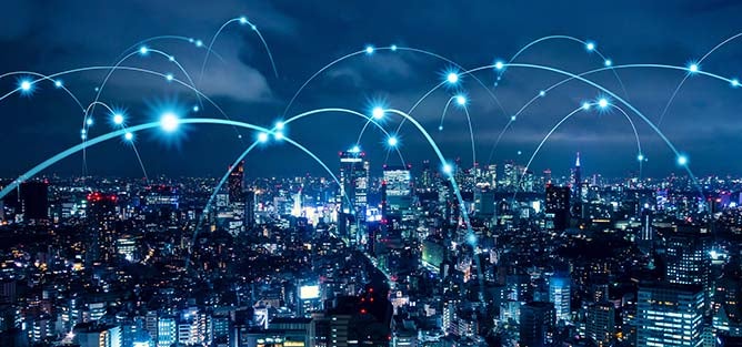 Image of a city skyline with line arcs over the buildings representing a connected network.