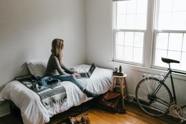 Girl sitting on bed working on computer